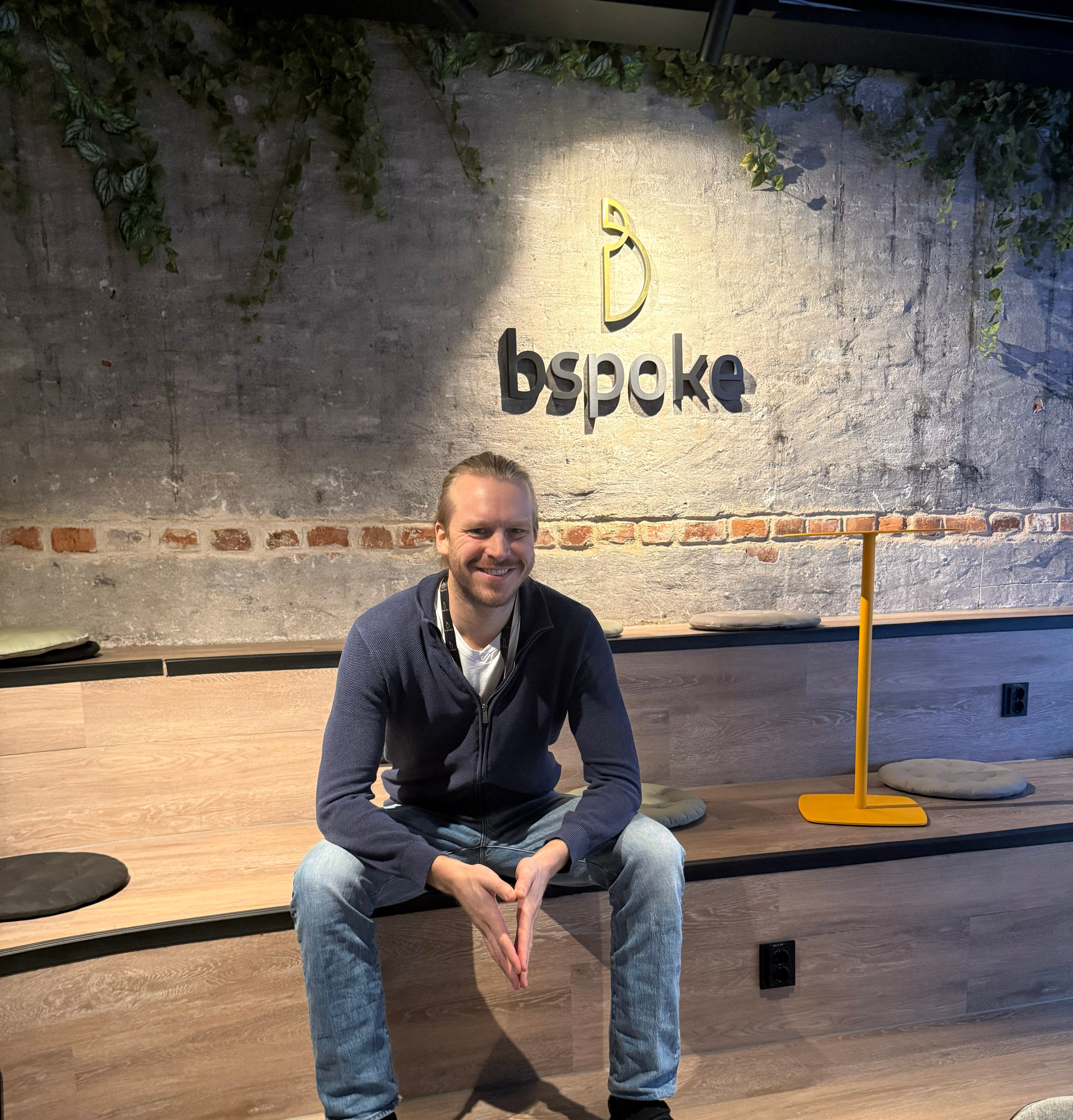 Lars sitter på tribunen foran en bspoke logo