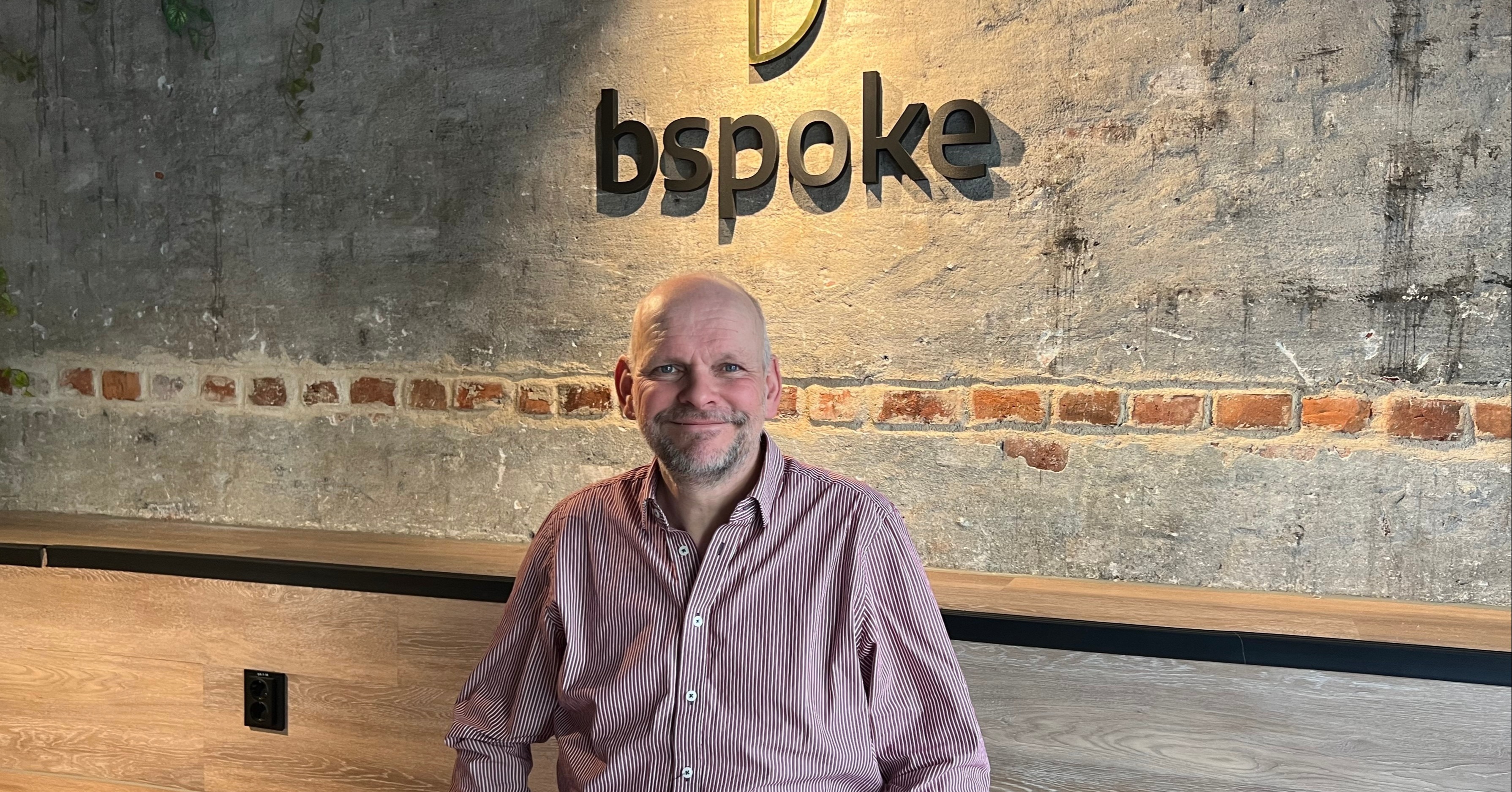 Lars sitter på tribunen foran en bspoke logo